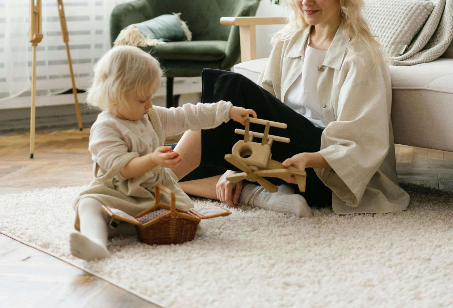 A mother and daughter enjoying quality time playing with wooden toys in a cozy living room.
