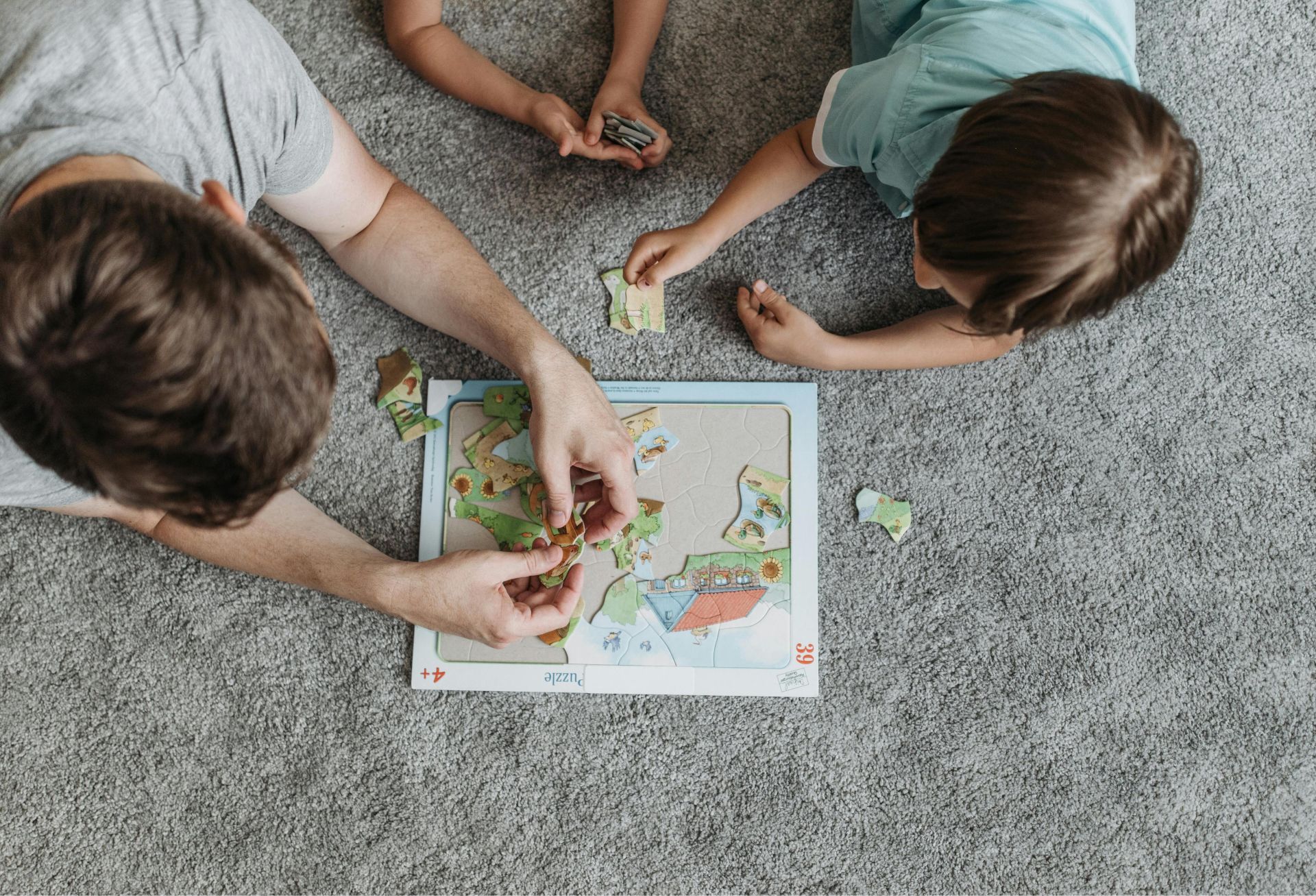 Father and children enjoying puzzle time together on a cozy carpeted floor.